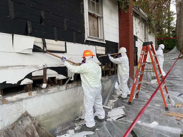 Asbestos contractors scraping residential siding