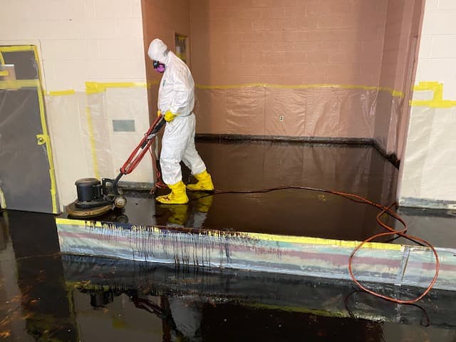 Asbestos contractor cleaning floor after abatement